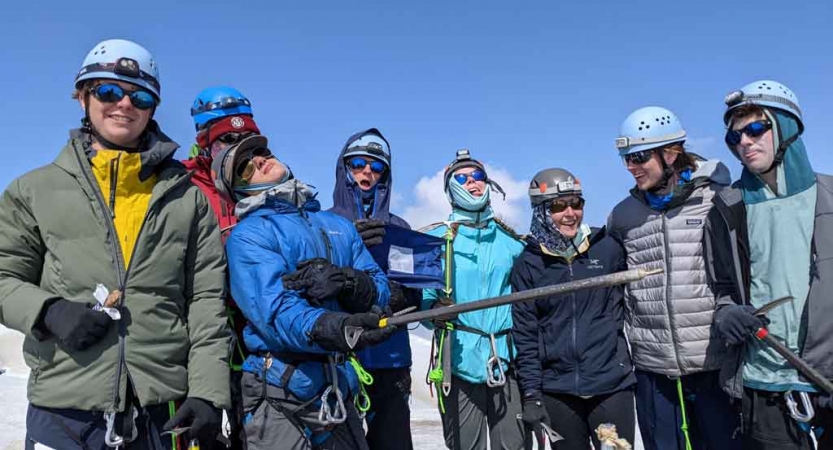 a group of people wearing mountaineering gear pose for a photo on an outward bound course